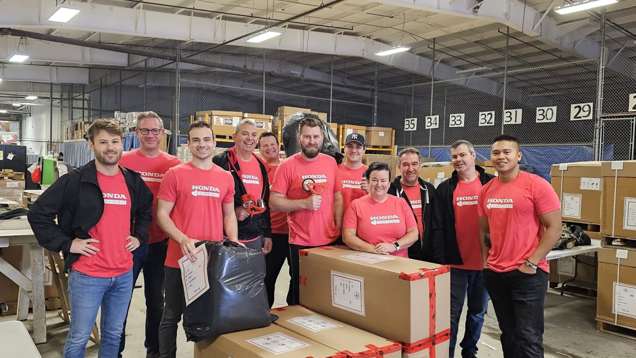 Un groupe d’employés portant des chandails Honda dans un entrepôt.