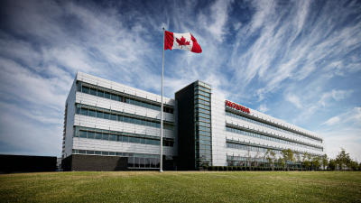 Plan large d’un bâtiment Honda avec un drapeau canadien sur un mât à l’avant-plan.