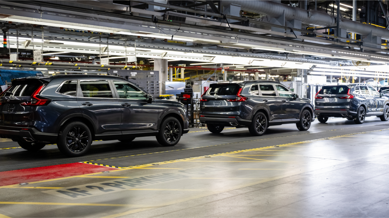 A line of cars in a factory interior being inspected.