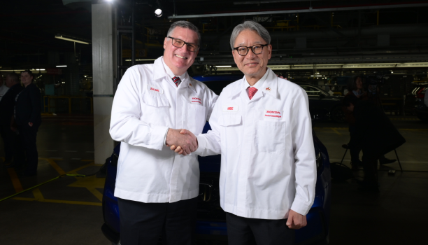 Two male Honda engineers in lab coats shaking hands.